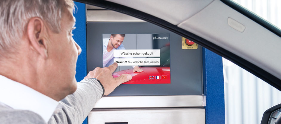 Mann wählt am TMann wählt am Touchterminal intuitiv das Waschprogramm in der Autowaschanlage